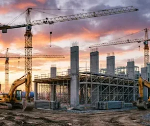 A busy construction site with cranes at sunset.
